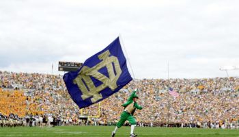 The Notre Dame Fighting Irish mascot carries the school flag on the field before a game against Michigan State.