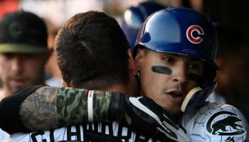 Chicago Cubs players Kyle Schwarber and Javy Baez embrace in the dugout.