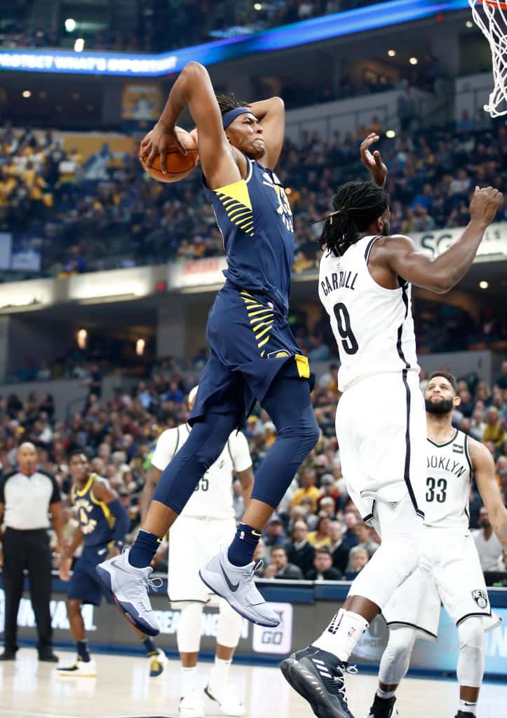 Myles Turner jumping to dunk the basketball with two hands on DeMarre Carroll