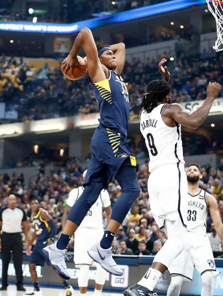 Myles Turner jumping to dunk the basketball with two hands on DeMarre Carroll