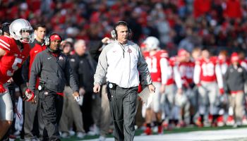 Urban Meyer coaches in a game in front of his sideline with players and coaches behind against the Indiana Hoosiers