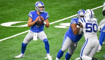 Matthew Stafford drops back to pass in a game against the Indianapolis Colts as Justin Houston drives in from the other side colliding with an offensive lineman