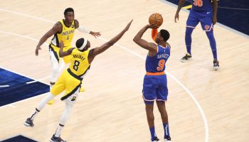 RJ Barrett rises up to shoot over the stretching hand of Justin Holiday with Victor Oladipo looking on in the background