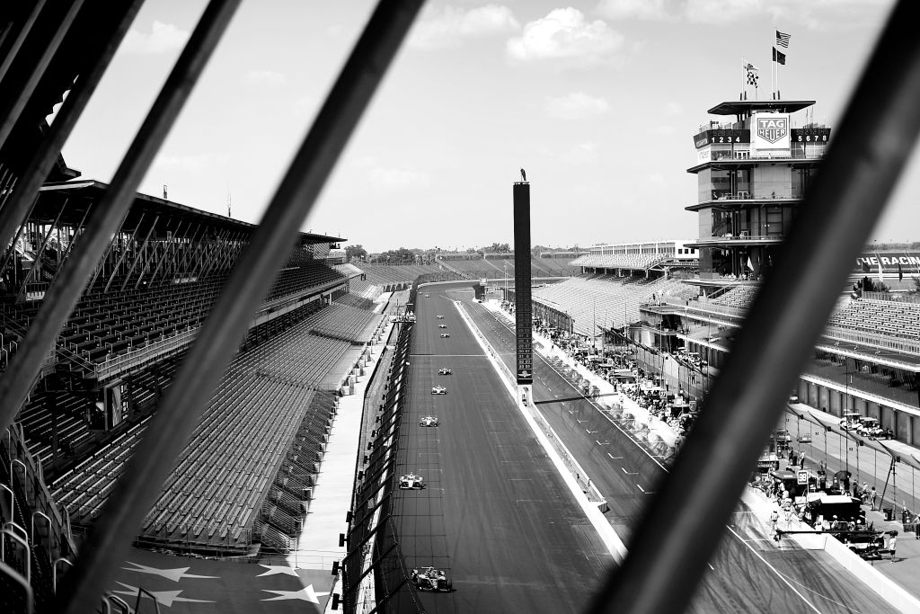 Straight away of Indinanpolis Motor Speedway with indy cars racing and no fans in the stands