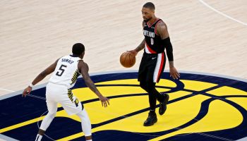 Damian Lillard dribbles the basketball on the Pacers logo at halfcourt closely defended by Edmond Sumner
