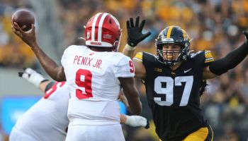 Michael Pennix Jr. throwing football with Iowa defender running at him