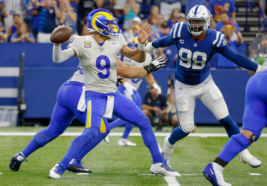 Matthew Stafford evades the pocket as he throws to a Rams receiver with Colts pass rushers after him
