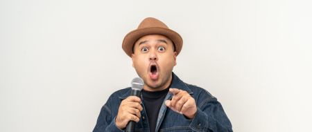 Shocked face young asian man singing song. Artist vocalist singer on isolated background. Confident man public speaking talking with microphone in studio.