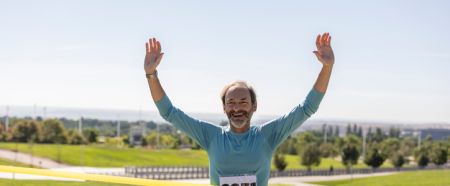 Happy senior running across the finish line - Mature man running marathon race. -