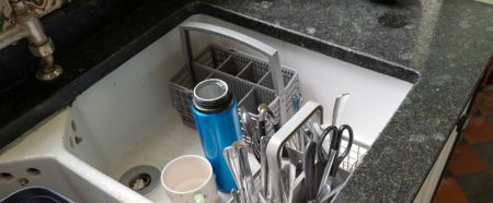 Recently cleaned kitchen utensils seen in a large ceramic sink.