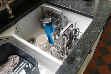 Recently cleaned kitchen utensils seen in a large ceramic sink.