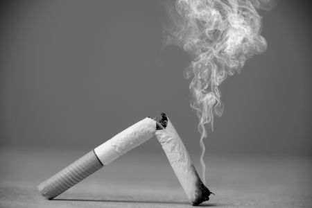 Broken smoking cigarette in black and white photo.