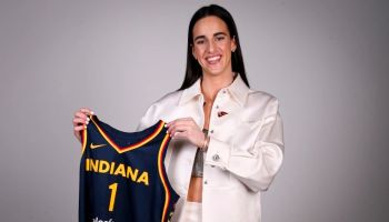 Caitlin Clark holding up Indiana Fever Jersey after WNBA Draft