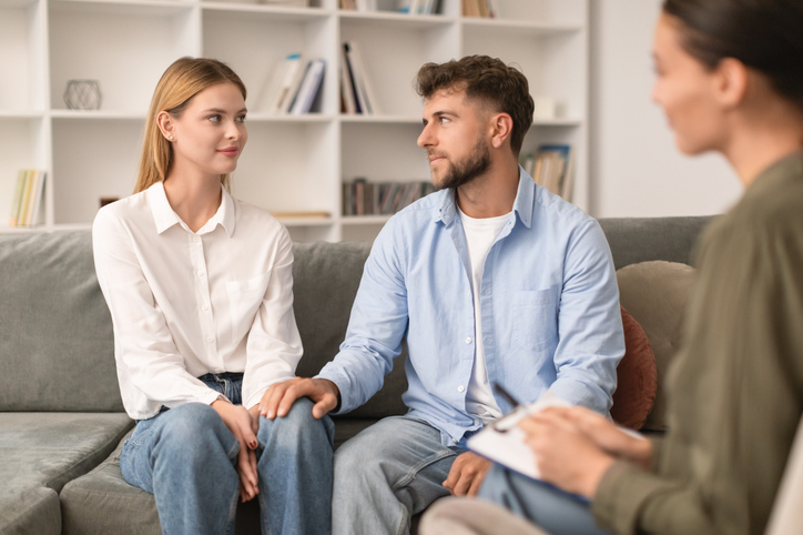 Young couple sitting on sofa engaging in couples therapy indoor