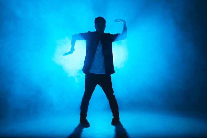 A dark silhouette of a singer on the stage, dancing alone during performance.