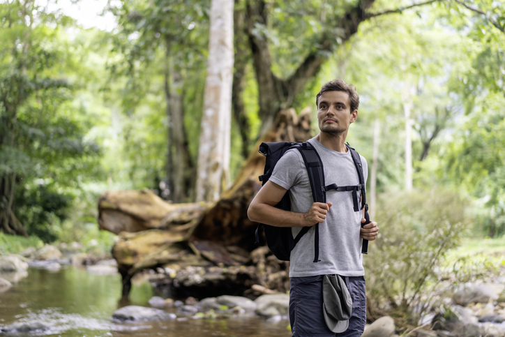 Confident smiling hiker standing against trees