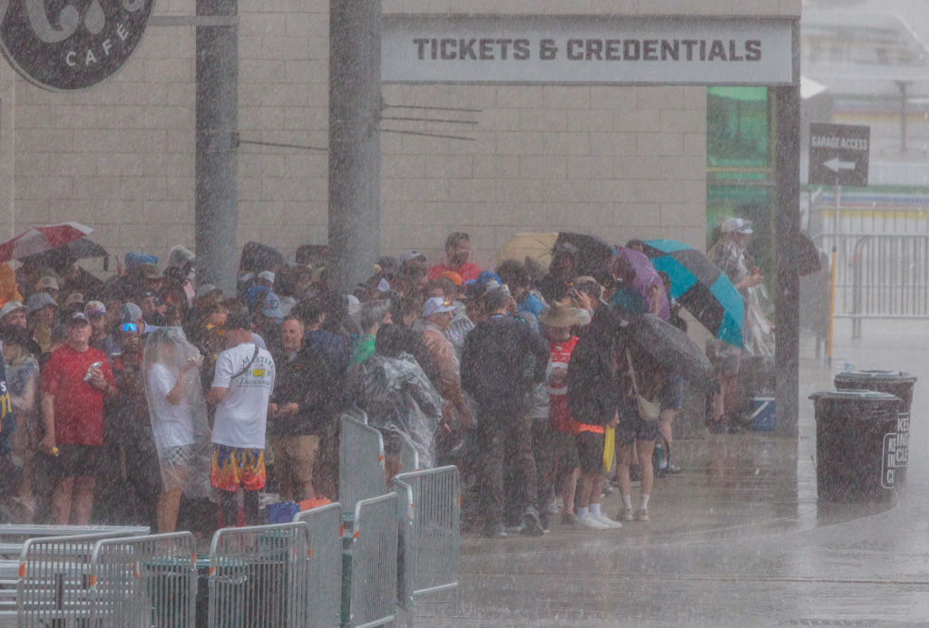 Fans are drenched during a rain delay before the 2024 Indy