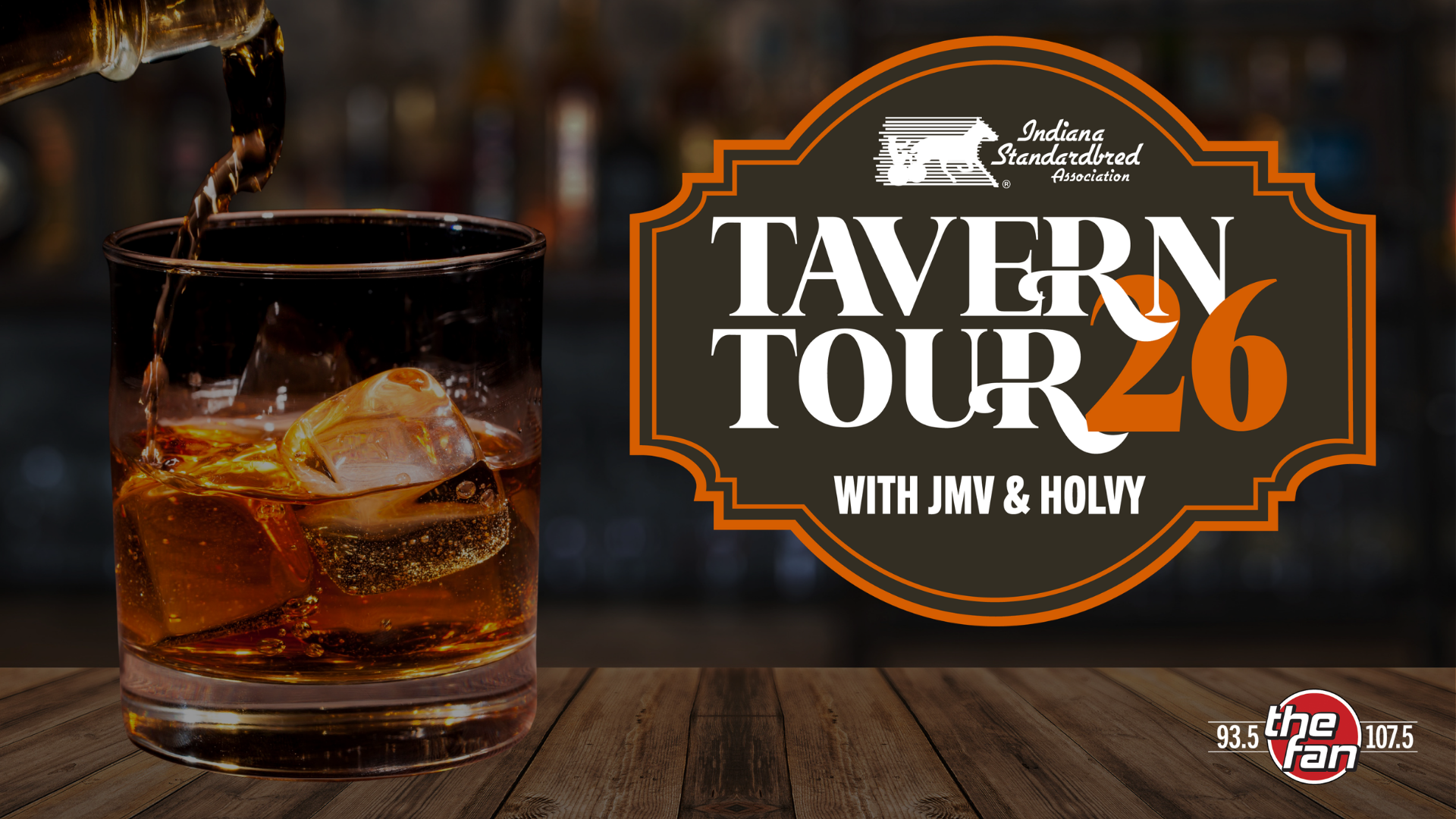 A glass of amber-colored liquor on a wooden table, with the "Tavern Tour 26" logo featuring the Indiana Standardbred Association branding.