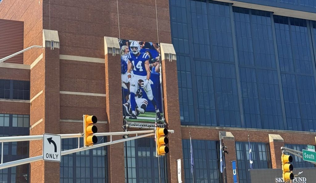 A large brick building with the "Lucas Stadium" sign, featuring a large image of a football player in a blue uniform on the side.