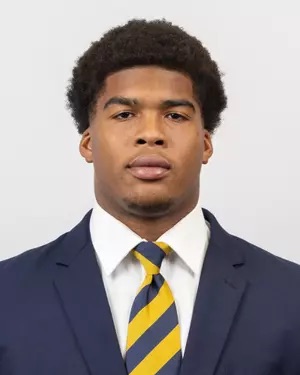 Headshot of a young African American man wearing a navy blue suit and yellow and navy striped tie.