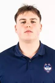 Headshot of a young man with short brown hair wearing a navy blue polo shirt.