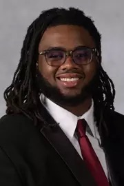 A smiling man wearing a suit and glasses.