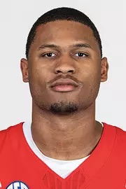 Headshot of a young Black man wearing a red sports jersey.