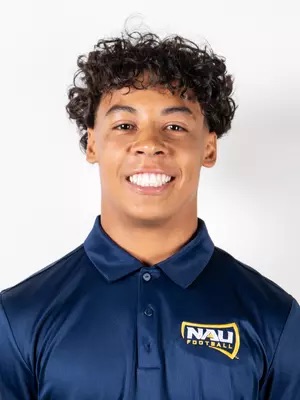 A smiling young man wearing a navy blue polo shirt with the "NAU" logo.